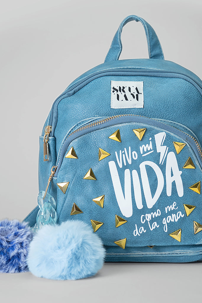 Mochila de polipiel efecto denim desgastado. Bolsillo delantero con tachuelas y serigrafía (Vivo mi vida como me da la gana) Cadena de pvc decorativa con pompones decorativos